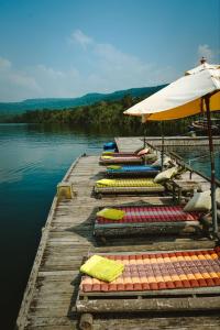 a dock with chairs and an umbrella on the water at Thansur Tatai Eco Resort in Tatai