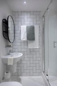 Baño blanco con lavabo y espejo en Keel House refurbished Studios, en Edimburgo