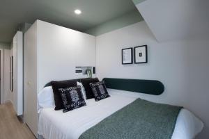 1 dormitorio con 1 cama con almohadas blancas y negras en Keel House refurbished Studios, en Edimburgo