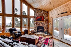 a living room with a stone fireplace in a log cabin at Serene Mountain Cabin Nestled Amongst the Pines - Alpenhaus in Fairplay