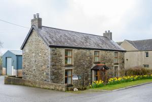 an old stone house with flowers in front of it at Grove Fort Self Catering Farmhouse in Finnis