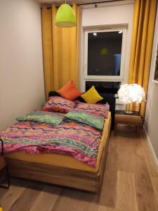 a bedroom with a bed with colorful pillows and a window at Sloneczny Apartament na 14 Kondygnacji z widiokiem na Bydgoszcz in Bydgoszcz