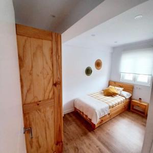 - une chambre avec un lit et une porte en bois dans l'établissement La Folia Vivienda vacacional, à San Vicente de la Barquera