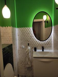 a bathroom with a white sink and a green wall at Sloneczny Apartament na 14 Kondygnacji z widiokiem na Bydgoszcz in Bydgoszcz