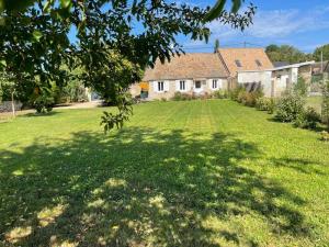 een tuin met een huis en een groot grasveld bij Le Gîte de la Melonnerie in Hardencourt-Cocherel