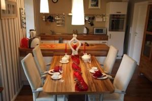 una mesa de comedor con sillas y una mesa de madera decorada en rojo. en Appartement in Klein Meckelsen mit Eigener Terrasse - b43026, en Klein Meckelsen