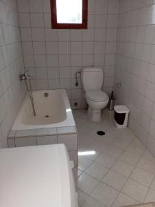 ein Badezimmer mit einer Badewanne, einem WC und einem Waschbecken in der Unterkunft Karpasi House in Karpásion