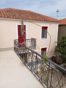 a white house with a red door and a balcony at Karpasi House in Karpásion