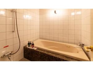 a bath tub in a bathroom with a shower at SHIZUKUISHI RESORT HOTEL - Vacation STAY 29546v in Shizukuishi