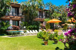 a hotel yard with chairs and an umbrella and flowers at Hacienda Buenaventura Hotel & Mexican Charm - All Inclusive in Puerto Vallarta
