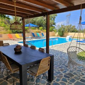 a patio with a table and chairs and a pool at Villa Farangi freistehend mit Pool und herrlichem Blick auf die Hügel und das Mittelmeer in Somatás