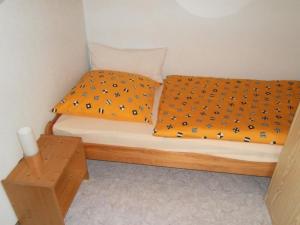 łóżko z pomarańczowym kocem z ptakami w obiekcie Ferienhaus Steinachtal in Franken bis 5 Personen - b48519 w mieście Marktgraitz