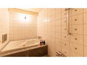 een witte badkamer met een bad en een douche bij SHIZUKUISHI RESORT HOTEL - Vacation STAY 29552v in Shizukuishi