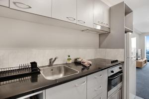 a kitchen with white cabinets and a sink at Hobson Apartment with Pool and View in Auckland
