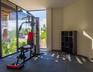 a gym with a treadmill and a chair in a room at Condo Moots 101 with private pool & rooftop yoga in Tulum