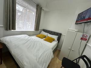 um pequeno quarto com uma cama com almofadas amarelas em Cosy Smart/Small Double Room in Keedonwood Road Bromley em Bromley
