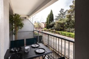 einen Balkon mit einem Tisch und Weingläsern darauf in der Unterkunft Le Cocon Verdoyant in Toulouse