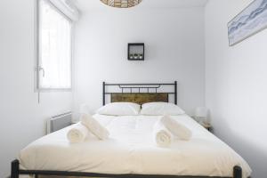 ein weißes Schlafzimmer mit einem großen weißen Bett mit weißen Kissen in der Unterkunft Le Cocon Verdoyant in Toulouse