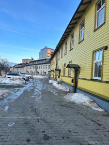 un edificio amarillo con nieve en el suelo junto a una calle en VILMSI 52 APARTMENTS, en Tallin