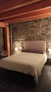 uma cama num quarto com uma parede de pedra em Cal cavalé em Vall de Castellbò