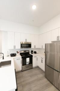 uma cozinha com armários brancos e um frigorífico de aço inoxidável em Chic 2-Bed Getaway Home-mins to NYC em Bayonne