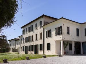 an old white building with black shuttered windows at Hotel Villa Policreti in Castello dʼAviano