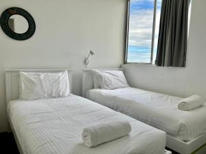 2 Betten in einem Zimmer mit weißer Bettwäsche und einem Fenster in der Unterkunft Ebbtide, Unit 37 in Forster