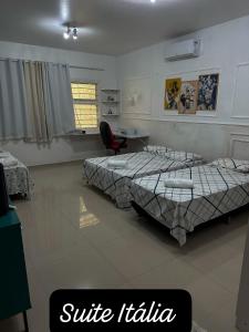 a bedroom with two beds and a desk and a chair at Residencial Mirandinha. in Boa Vista