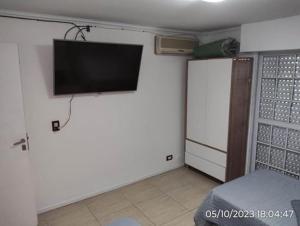 1 dormitorio con TV de pantalla plana en la pared en Departamento “Edificio Manuelita” en Resistencia