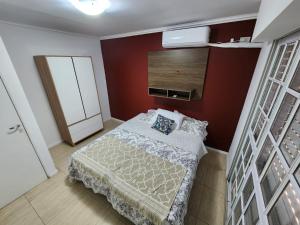 um pequeno quarto com uma cama e uma parede vermelha em Departamento “Edificio Manuelita” em Resistência