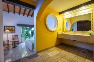 a bathroom with yellow walls and a sink and a bedroom at Hacienda Buenaventura Hotel & Mexican Charm - All Inclusive in Puerto Vallarta