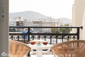 a table with two cups and two chairs on a balcony at Agora Central Home in Chalkida