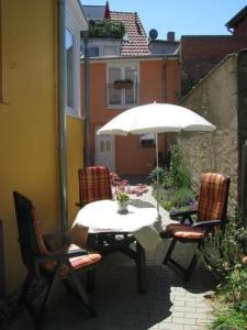 een tafel en stoelen met een parasol op een patio bij Moderne Ferienwohnung mitten in der Greifswalder Innenstadt in Greifswald