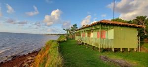 a house on the shore of a body of water at Pousada Bosque dos Aruãs in Salvaterra