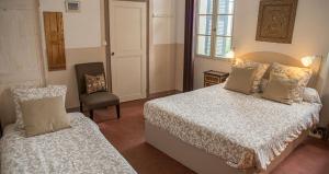 a bedroom with two beds and a chair and a window at Chambres et table d'hôtes Au Brabo in Mormoiron
