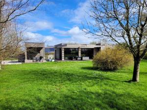 una casa con un patio verde con un árbol en Villa en bois à la campagne - 20 min de Rouen, en Morgny-la-Pommeraye