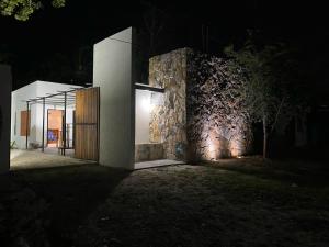a building with a stone wall at night at Casa Costa Rosa - Habitación Mar in Yuluc