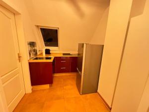 La cuisine est équipée d'un réfrigérateur en acier inoxydable et de placards bruns. dans l'établissement Cozy Wohnung in Meerbusch, à Meerbusch