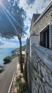 un edificio de piedra con un árbol al lado de una carretera en Villa Furoris Apartment, en Furore