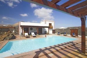a swimming pool with chairs and a house at Sehr großzügig und modern eingerichtetes Ferienhaus mit privatem Pool und Sonnenterrassen im eigenen Garten in Tías
