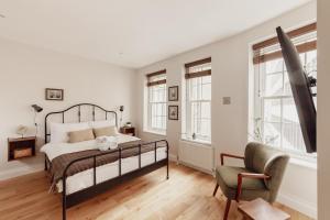 a bedroom with a bed and a chair and windows at Holborn Townhouse in London