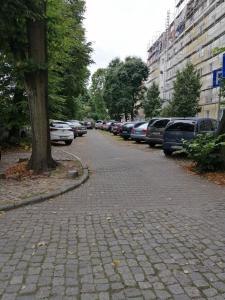 una calle adoquinada con coches estacionados junto a un árbol en Apartament Mazowiecka, en Szczecin