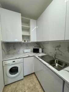 een witte keuken met een wastafel en een wasmachine bij Sofiamarholidays - Casa Praia Mar in Portimão