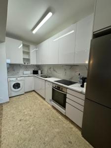 cocina con armarios blancos, lavadora y secadora en Sofiamarholidays - Casa Praia Mar en Portimão