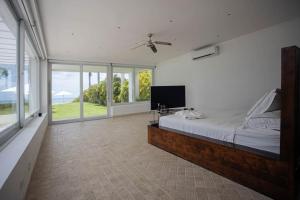 a bedroom with a large bed and large windows at Villa con piscina en frente al mar con servicios in San Carlos