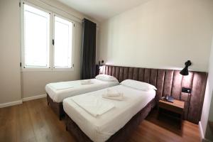a hotel room with two beds and two windows at HOTEL LIBERTAS in Vlorë