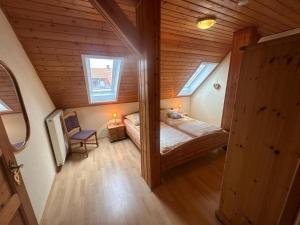 a small attic bedroom with a bed and two windows at Ferienwohnung Gut-Wattberg in Hofgeismar