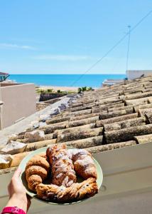 a person holding a plate of pastries on a ledge at Mare del Sud , Lovely apartment with sea view in Pozzallo