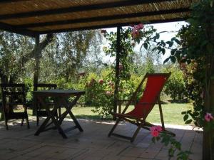 een patio met een tafel en een rode stoel bij Ferienwohnung in Barberino Tavarnelle mit Privatem Garten - b58103 in San Donato in Poggio