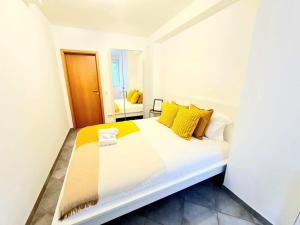 a white bed with yellow pillows in a room at Spacious one bedroom with garden&balcony in Pulvermühle